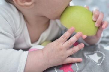 baby 6 months old with a green apple in his hand