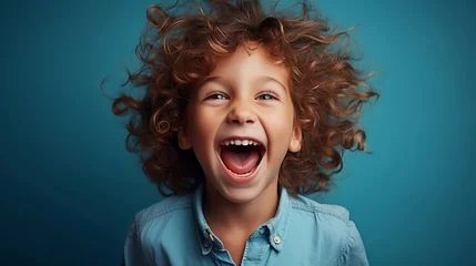 Tuinposter Joyful cute little child boy happy portrait on blue background. © mariiaplo