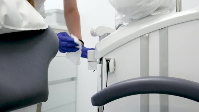 cleaning dental office wipe moisture with sterile cloth equipment sink for spitting dental chair disinfection neatness cleanliness neatness girl nurse with wet napkin in hygiene gloves. cleaning