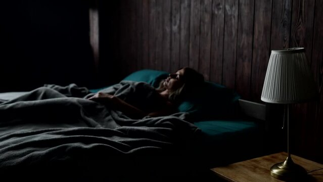 single woman sleeping in bed in morning, cinematic shot of bedroom in dark tones, loneliness