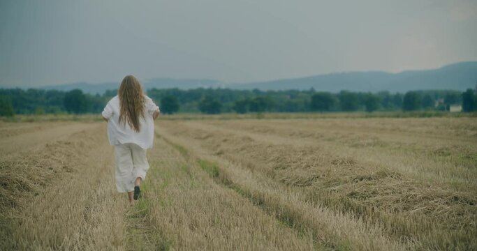 Woman Walking On Footpath In Meadow