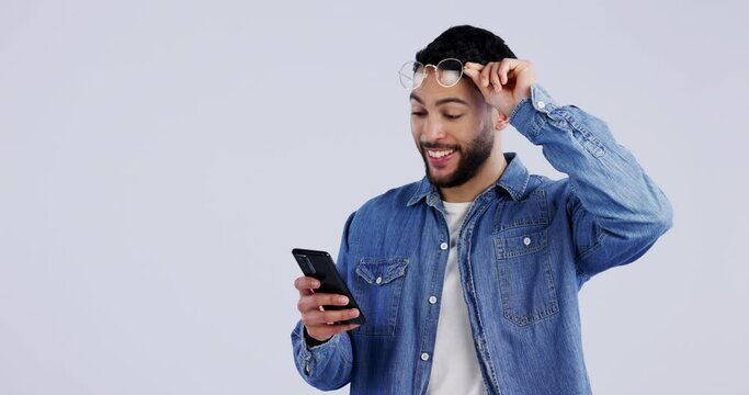 Meme, surprise or man excited by phone notification in studio for online bonus or fashion sale. Glasses, shock or happy person on blue background for mobile app promotion, message or good news