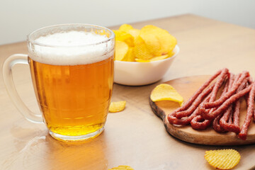 Beer and snack. Beer, Grilled sausage, potato chips on bar table. Beer pub set. Large beer mug with fried sausages.