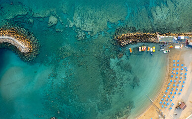 Drone aerial of tropical sandy beach. Beach umbrellas people swimming and relaxing. Summer vacations