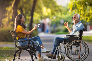 Senior man in wheelchair and his daughter having fun in park - 647781694