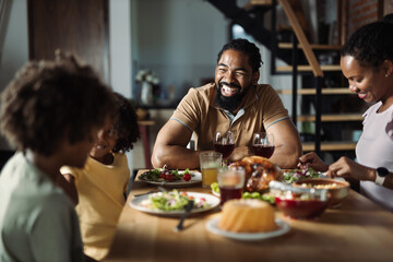 Happy African American family enjoying in meal at dining table