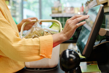 Close-up of customer using cash register to buy products herself in supermarket - obrazy, fototapety, plakaty
