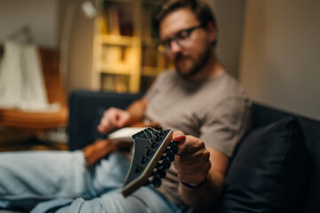 Sharpened view of a mans hand tuning the guitar.