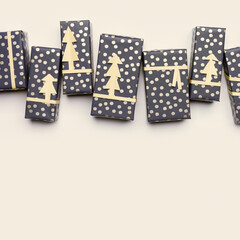 Christmas card with wrapped paper gift boxes on beige fon, stylish packaging presents for winter holidays. Handmade New Year gifts decorated cutting paper fir. Xmas, New Year background