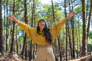 Woman with open arms looking up while enjoying nature. Freedom concept.