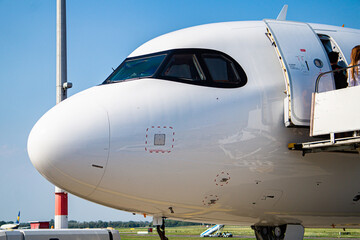 Detailed view of aircraft nose, windshield and door. Boarding airplane on airport runway.