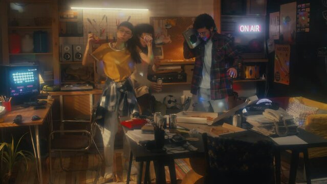Young men and woman wearing casual clothes eating pizza and dancing at party in garage office, 90s aesthetics
