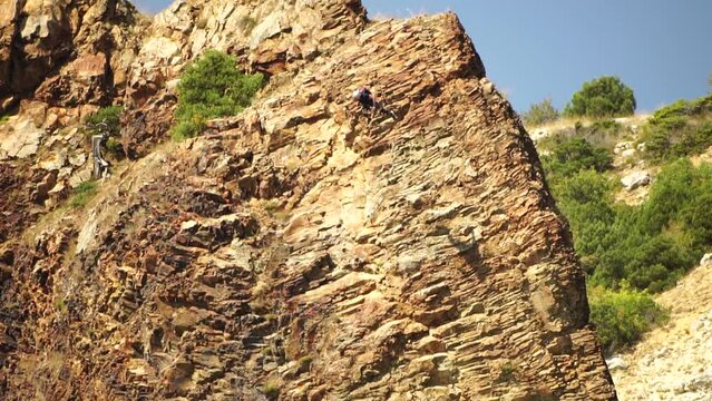 Male base jumper jumps off edge of volcanic rock and opens his parachute. Extreme sport. Skydiving and parachuting daredevils B.A.S.E jump from great heights. Slow motion