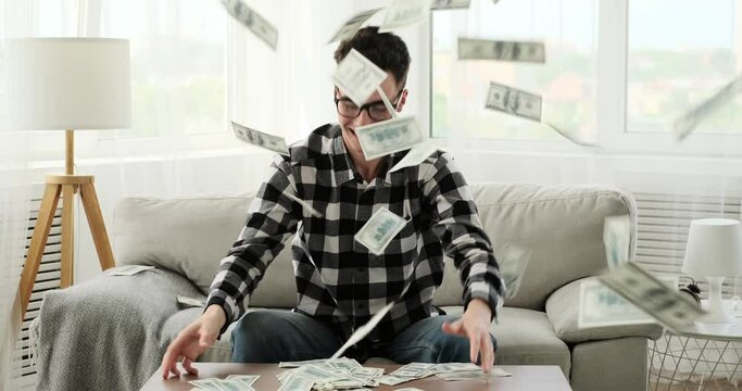 Overflowing with excitement, a Caucasian man goes wild and scatters money in the living room. The scene captures his exuberant energy and the joyous abandon that comes with moments of euphoria.