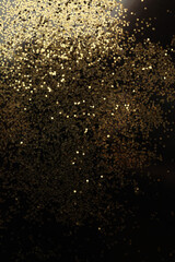 Fototapeta na wymiar Gold (bronze) glitter shine dots confetti on black. Abstract light blink sparkle vertical backgound.