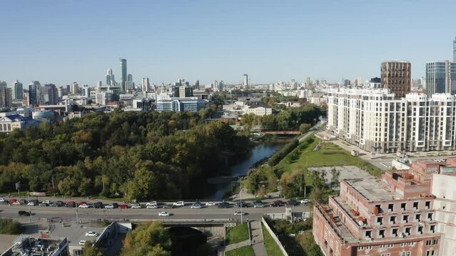 Aerial view of a modern big city with central streets on a summer day. Stock footage. Green park and river near buildings.