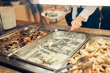 A steel tray with food in the school's self-service buffet. The child puts food on his plate. High quality photo
