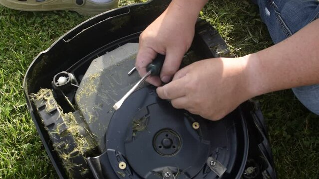 A man changing the blade of a robotic mower