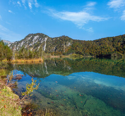 Fototapeta premium Peaceful autumn Alps mountain lake with clear transparent water and reflections. Almsee lake, Upper Austria.