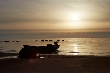 Obraz premium Beautiful landscape during the sunset with sky and sea coloured by the sunset and small boat on the shore