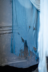 torn blue fabric. Fabric with holes. Torn ventilated curtain on old one.