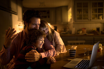 Young family watching a movie on the laptop at night at home
