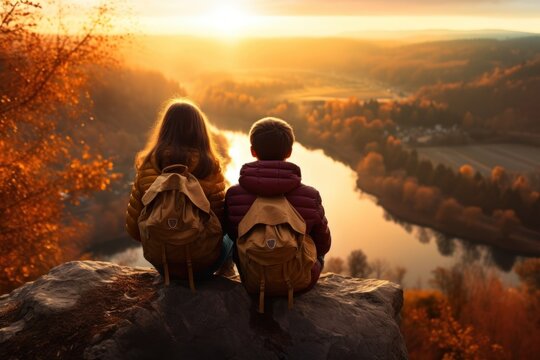 A picture of a couple of kids sitting on top of a rock. Perfect for illustrating friendship, adventure, and outdoor activities.
