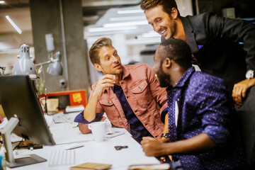 Young diverse group of businessmen using a computer in the office of a startup company
