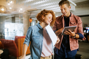 Young Caucasian woman and man using the tablet in the office of a startup company