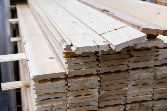 stacks of raw wooden tongue and groove boards, close-up view of the ends.