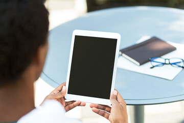 Young businessman sitting at workplace holding digital tablet with blank screen, checking mail, mockup, remote work. Business, technology concept 