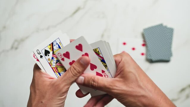 Hands are flipping through playing cards at the end of a poker game