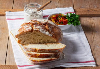 Round yeast bread made from white and whole grain flour, tomato salad and pate on a wooden...