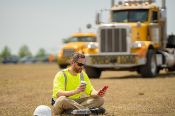 Worker taking break from work drinking coffee and resting sitting on grass. Builder worker relaxed...