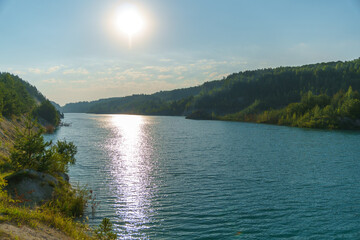 View of the lake among the lush green trees in the forest. Trees grow along the river and are reflected in the clear water. Natural landscape in the forest. River in the forest. uncontaminated nature