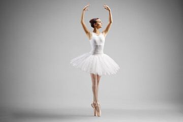 Ballerina in a white dress dancing with arms up
