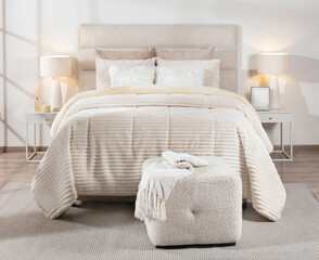 Interior of a Scandinavian Modern Bedroom with a Bed Featuring a White Cozy Coverlet with Beige Pillows and Modern Bedside Tables with Lamps.