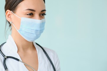 Portrait of young beautiful female medical worker,wearing uniform and protective face mask - Powered by Adobe