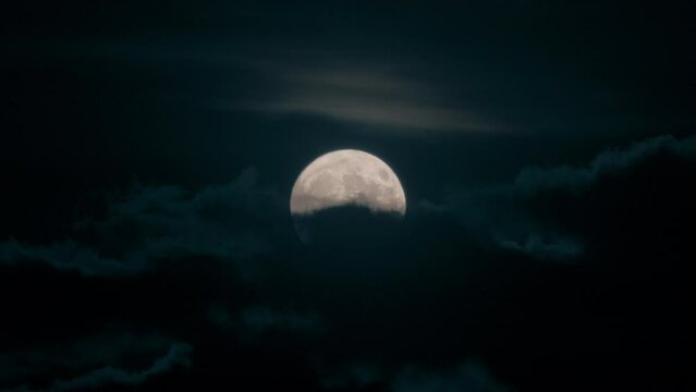 Moon hidden in the sky between the clouds and in the darkness of the night