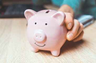 The girl puts her savings in a piggy bank.