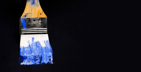 Brush with blue oil paint on the dark background.