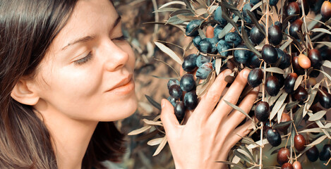 Girl holds a branch with black olives in her hands.