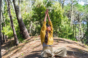 Woman about to meditate with hands clasped to the sky on the woods