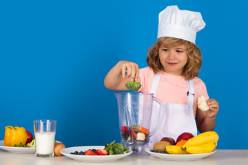 Kid boy in chef hat and apron hold broccoli cooking preparing meal. Little cook with vegetables at kitchen. Natural kids food.