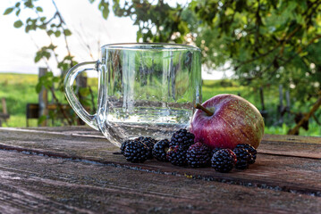 Mug, apple and blackberry on the table - obrazy, fototapety, plakaty