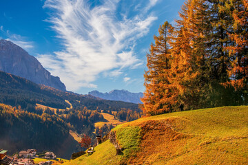 A captivating view of Val Gardena in the Dolomite Alps, Italy, adorned with autumn hues and bathed in sunlight