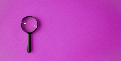 Magnifying glass, magnifying glass in a black frame on a purple background.  Concept research, objects magnification.  Flat top view.  Space for copying text.