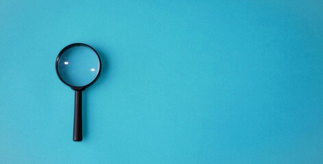 Magnifying glass, magnifying glass in a black frame on a blue background.  Concept research, objects magnification.  Flat top view.  Space for copying text.