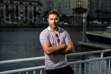 Portrait of handsome male model outdoor. Stylish man dressed in polo. Fashion male posing on the street background. Urban style. Young man walk through the city. Wealthy businessman posing next to