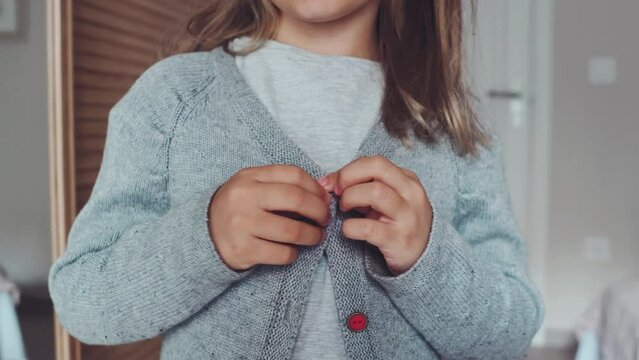 Close up hands button up skill for children, develop motor coordination, child practise buttoning grey jacket. kid learn functional dressing Montessory skills, sensory. get dressed lifedevelopmental.